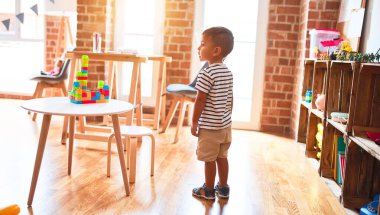 Anaokulunda bir sürü oyuncakla bekleyen güzel bir çocuk.