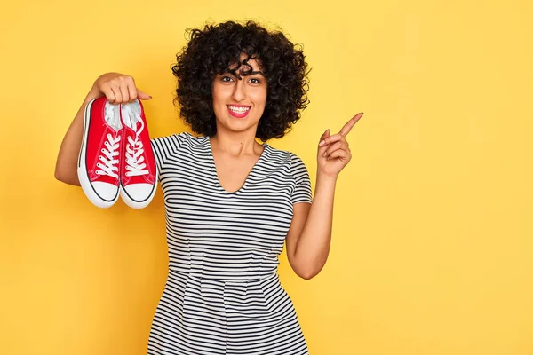 Jonge Arabische Vrouw Met Krullend Haar Houden Casual Sneakers Geïsoleerde — Stockfoto