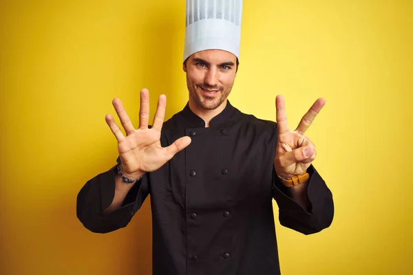 年轻厨师 身穿制服 头戴帽子 站在孤立的黄色背景上 露出七号手指 面带微笑 自信而快乐 — 图库照片