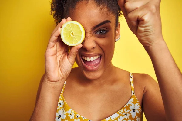 若いアフリカ系アメリカ人の女性がレモンのスライスを持っている孤立した黄色の背景にいらいらし 怒りで叫んで 狂気と大声で手を上げ 怒りの概念 — ストック写真