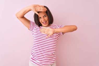 İzole edilmiş pembe arka plan üzerinde duran çizgili tişört giyen genç ve güzel bir kadın. Gülümseyen, güler yüzlü, elleri açık bir şekilde dikizleme oyunu oynayan. Şaşırdım ve çıktım.