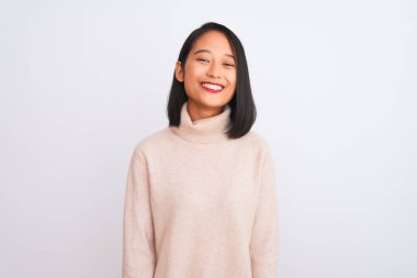 Balıkçı yaka kazak giyen genç Çinli bir kadın izole edilmiş beyaz arka planda mutlu ve havalı bir gülümsemeyle dikiliyor. Şanslı kişi..