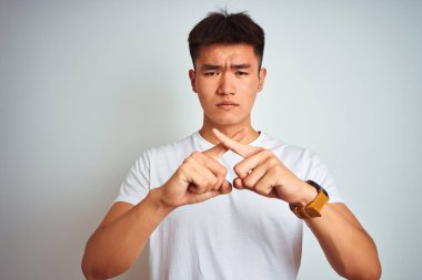 Asyalı genç bir Çinli tişört giyiyor. İzole edilmiş beyaz arka plan üzerinde duruyor. Reddedilme ifadesi negatif işaret veriyor.