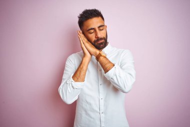 Genç Hintli iş adamı zarif bir gömlek giyer, pembe arka planda dikilir uyur, yorgun düşler kurar ve elleri ile birlikte poz verir, kapalı gözlerle gülümserdi..