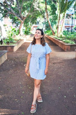 Güneşli bir yaz gününde yeşil parkta mutlu ve neşeli gülümseyen güzel bir kadın.