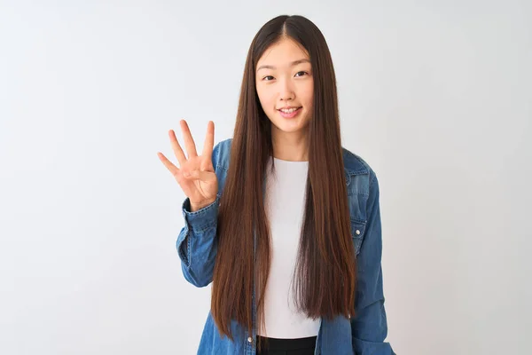若いです中国人女性身に着けているデニムシャツ上に立って隔離された白い背景を示すと指の数4で指摘しながら 自信と幸せ — ストック写真