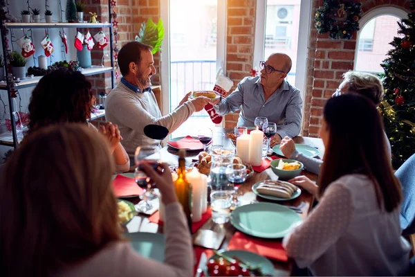 Family and friends dining at home celebrating christmas eve with traditional food and decoration, taking picture all together