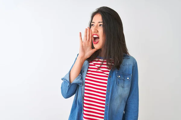 白い背景に縞模様のTシャツとデニムのシャツを着た若い中国人女性が大声で叫び 口の上で手で横に大声で叫ぶ コミュニケーションの概念 — ストック写真