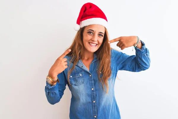 孤立した背景にクリスマスの帽子をかぶっている若い美しい赤毛の女性は 明るい表情と指の歯と口で指して笑っています 歯科衛生の概念 — ストック写真