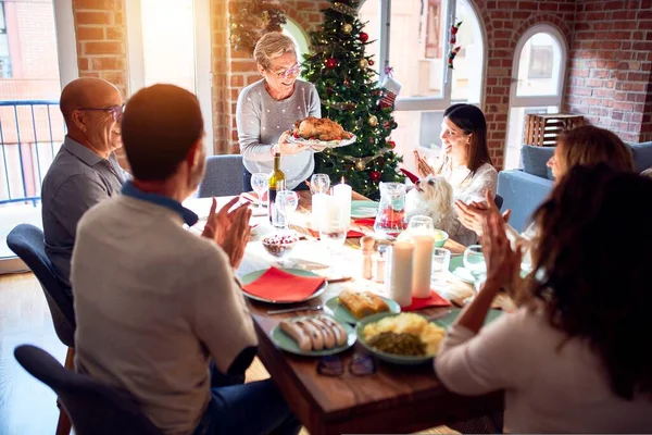 Family and friends dining at home celebrating christmas eve with traditional food and decoration, showing proud turkey cooking