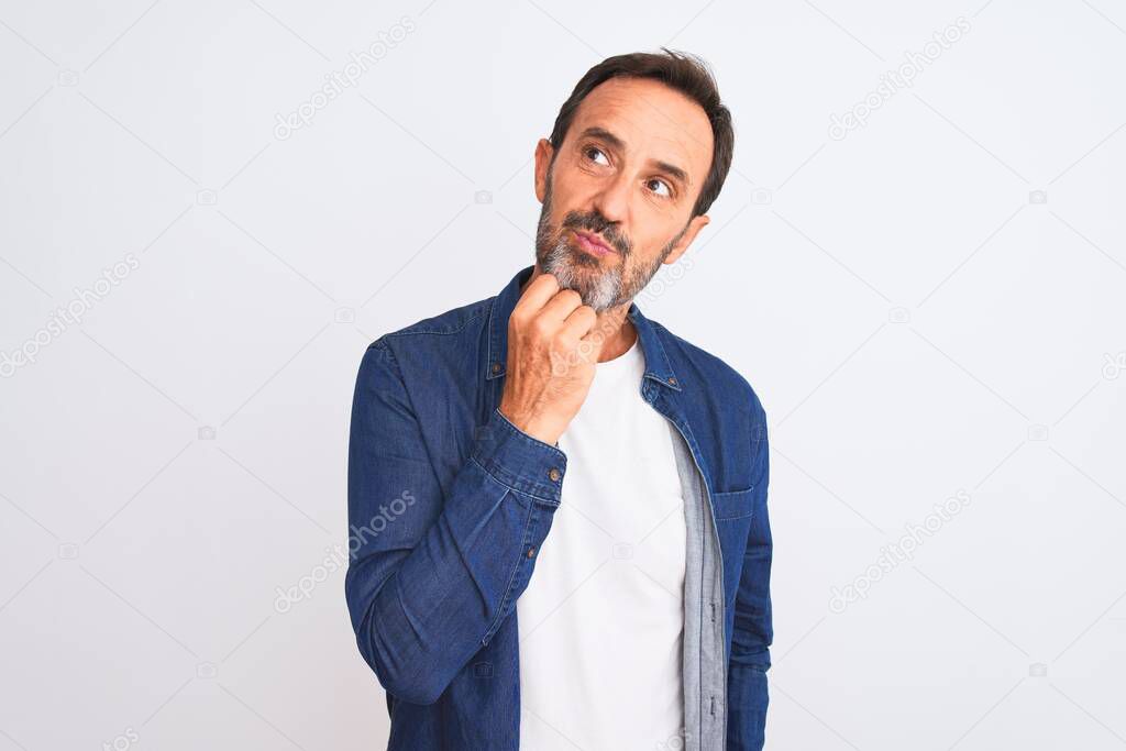 Middle age handsome man wearing blue denim shirt standing over isolated white background with hand on chin thinking about question, pensive expression. Smiling with thoughtful face. Doubt concept.