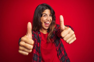 Kırmızı izole edilmiş arka plan üzerinde duran sıradan bir ceket giyen genç ve güzel bir kadın. Elleriyle, hayal kırıklığına uğramış ve ciddi bir yüzle jest yapıyor.