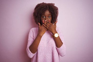 İzole edilmiş pembe arka plan üzerinde duran Afrikalı genç bir Afro kadın yanlışlıkla ağızlarını kapatarak şok geçirdi. Gizli konsept.