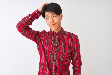 İzole edilmiş beyaz arka planda duran sıradan kırmızı tişörtlü genç Çinli adam soru sormayı merak ediyor. Şüpheyle kararsız, kafa kafaya düşünerek. Düşünceli kavram.