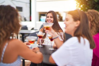 Güzel bir grup kadın restoranın terasında oturmuş kokteyller içiyor konuşuyor ve gülümsüyor.