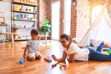 Güzel öğretmen ve küçük çocuk anaokulunda trenle oynuyor.