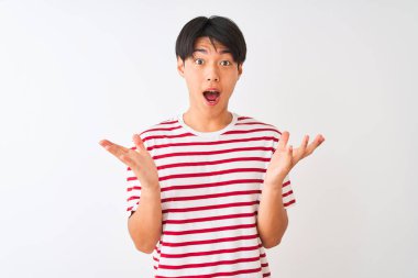 Sıradan çizgili tişört giyen genç Çinli bir adam izole edilmiş beyaz arka planda durmuş çılgın ve başarıyı kollarını kaldırıp heyecanla haykırarak kutluyor. Kazanan konsept