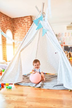 Anaokulunda bir sürü oyuncakla oynayan sevimli bir çocuk.
