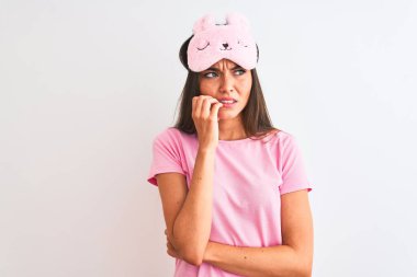 İzole edilmiş beyaz arka plan üzerinde duran uyku maskesi takan genç ve güzel bir kadın elleri ağız ısıran tırnaklarla gergin ve stresli görünüyor. Endişe sorunu.