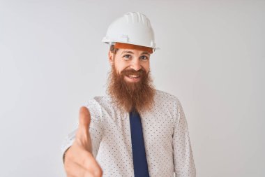İzole edilmiş beyaz arka plan üzerinde güvenlik kaskı takan genç kızıl saçlı mimar dostça gülümseyerek selamlama ve hoş geldin diyor. Başarılı bir iş..