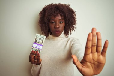 Yalnız beyaz arka planda duran, elinde dolar tutan Afrikalı genç bir kadın dur işareti yapıyor ciddi ve kendinden emin bir ifadeyle, savunma jesti yapıyor.