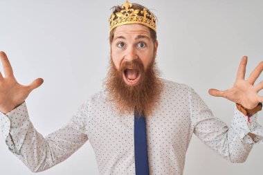 Genç kızıl saçlı İrlandalı işadamı izole edilmiş beyaz arka planda krallık tacını takıyor çılgın ve başarıyı kollarını kaldırıp heyecanla haykırarak kutluyor. Kazanan konsept