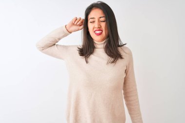 Balıkçı yaka kazak giyen güzel Çinli kadın izole edilmiş beyaz arka planda duruyor yorgun ve rahat, uykulu ve sabahın erken saatlerinde esniyor.