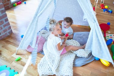 Anaokulundaki bir sürü oyuncağın etrafında battaniyenin üstünde oynayan güzel bebekler.