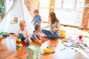 Güzel öğretmen ve bir grup çocuk anaokulunda bir sürü oyuncakla oynuyorlar.