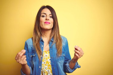Sarı arka planda duran genç ve güzel bir kadın. Elleriyle para hareketi yapıyor. Maaş istiyor.