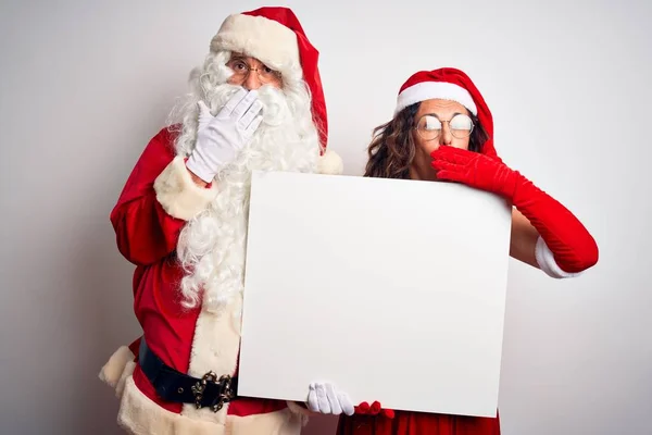上了年纪的夫妇 身穿圣诞老人的服装 手拿着横幅挂在孤独的白色背景封口上 为自己的错误 恐惧的表情 沉默中的恐惧 神秘的概念而感到羞愧 — 图库照片