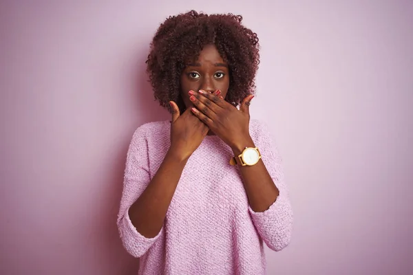 孤立したピンクの背景の上に立ってセーターを着ている若いアフリカのアフロ女性は間違いのために手で口をカバーショックを受けた 秘密概念 — ストック写真