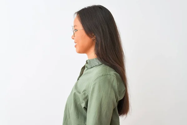若いです中国人女性身に着けています緑のシャツと眼鏡上の隔離された白い背景の上に横に探しています 自信を持って笑顔で自然な顔でプロファイルポーズ — ストック写真