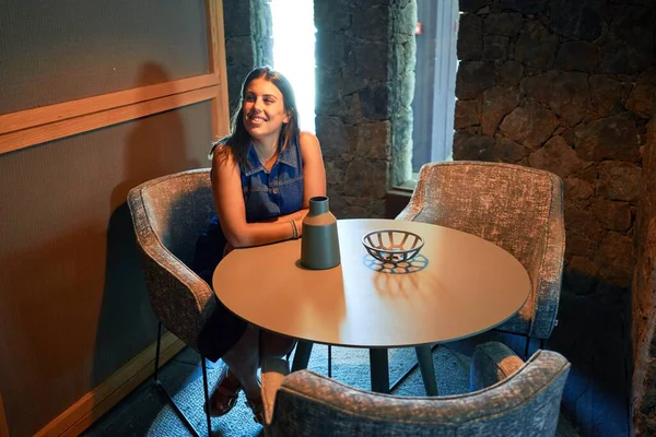 Young beautiful woman sitting at restaurant enjoying summer vacation