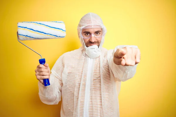 Joven Con Equipo Pintor Sosteniendo Rodillo Pintura Sobre Fondo Amarillo — Foto de Stock