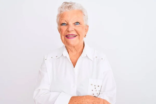 Senior grey-haired woman wearing elegant shirt standing over isolated white background happy face smiling with crossed arms looking at the camera. Positive person.