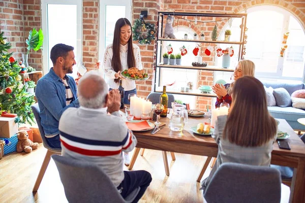 Beautiful family meeting smiling happy and confident. Person standing holding roasted turkey celebrating Christmas at home