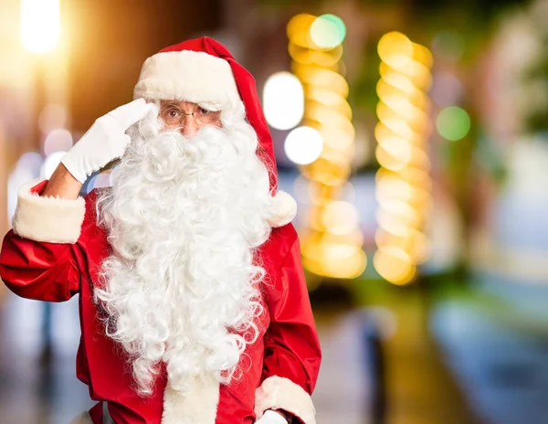 Middle age handsome man wearing Santa Claus costume and beard standing Shooting and killing oneself pointing hand and fingers to head like gun, suicide gesture.