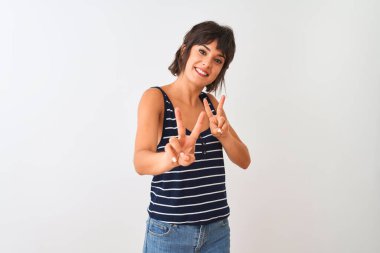 İzole edilmiş beyaz arka planda duran çizgili tişört giyen genç ve güzel bir kadın kameraya bakıp zafer işareti yaparken gülümsüyor. İki numara..