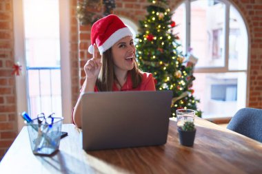 Noel 'de Noel Baba şapkası takmış, dizüstü bilgisayarla çalışan güzel bir kadın başarılı bir fikri işaret ediyor. Heyecanlı ve mutlu. Bir numara..
