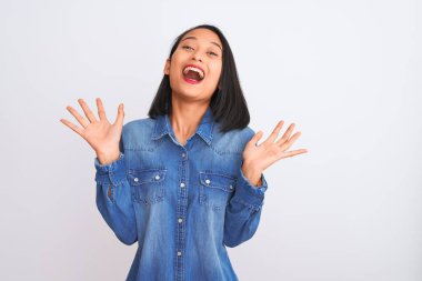 Kotlu tişört giyen genç ve güzel bir Çinli kadın izole edilmiş beyaz arka planda durmuş çılgın ve başarıyı kollarını kaldırıp heyecanla haykırarak kutluyor. Kazanan konsept