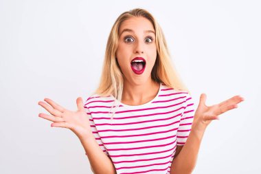 Pembe çizgili tişört giyen genç ve güzel bir kadın izole edilmiş beyaz arka plan üzerinde durmuş çılgın ve başarıyı kollarını kaldırıp heyecanla haykırarak kutluyor. Kazanan konsept