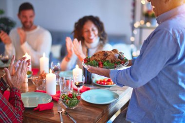 Mutlu ve kendinden emin gülümseyen güzel bir aile. Kızarmış hindiyi göstermek ve evde Şükran Günü 'nü kutlamak.