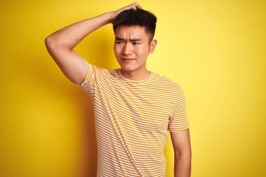 İzole edilmiş sarı arka plan üzerinde duran Asyalı genç bir Çinli adam soru sormayı merak ediyor. Şüpheyle kararsız, kafa kafaya düşünerek. Düşünceli kavram.