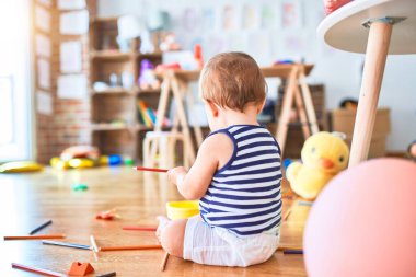 Anaokulunda bir sürü oyuncakla oynayan sevimli bir çocuk.