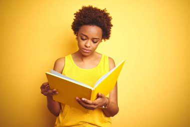 Sarılar üzerine kitap okuyan Afro-Amerikalı bir kadın. Kendini beğenmiş bir ifadeyle izole edilmiş arka plan.