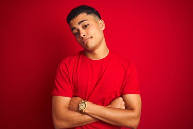 İzole edilmiş kırmızı arka plan üzerinde duran genç Brezilyalı adam uykulu ve yorgun görünüyor, yorgunluktan yorgun ve akşamdan kalma, sabahları tembel gözler..