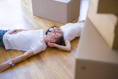 Genç güzel çift karton kutular etrafında yeni evde yatarken