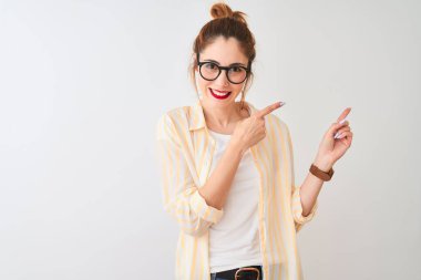 Kızıl saçlı kadın çizgili gömlek ve gözlük takıyor. İzole edilmiş beyaz arka planda duruyor. Gülümsüyor ve kameraya bakıyor..