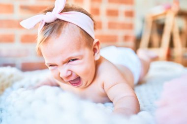 Güzel bebek battaniyenin üzerine uzanmış evde mutlu bir şekilde gülümsüyor. Yüzünde gülümsemesi olan yeni doğmuş bir bebek. Rahatlıyor ve dinleniyor.